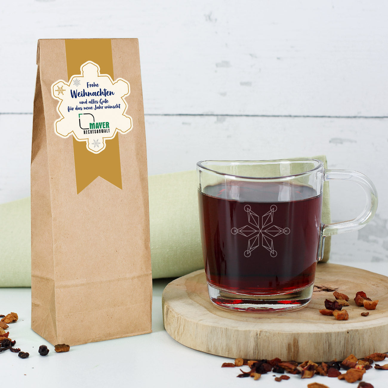 Set aus Tee und einem passenden Glas mit Schneeflocken-Motiv und Logo