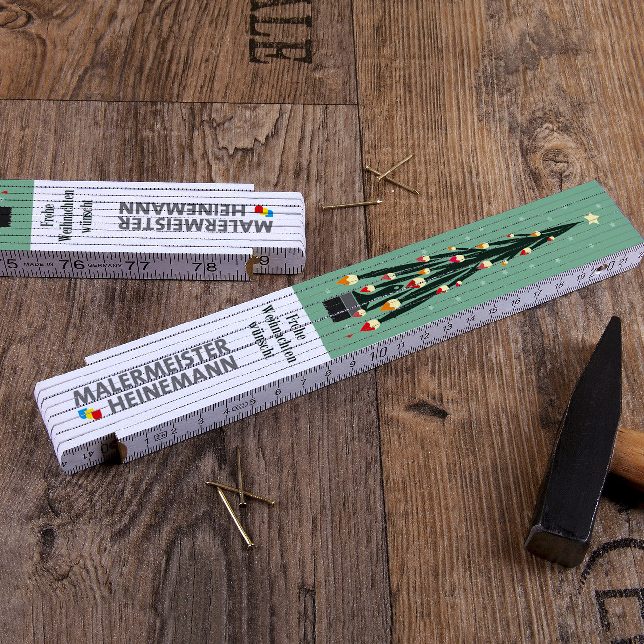 Zollstock mit einem Weihnachtsbaum aus Pinseln und Firmenlogo