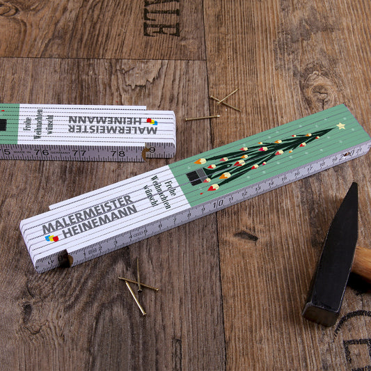 Zollstock mit einem Weihnachtsbaum aus Pinseln und Firmenlogo