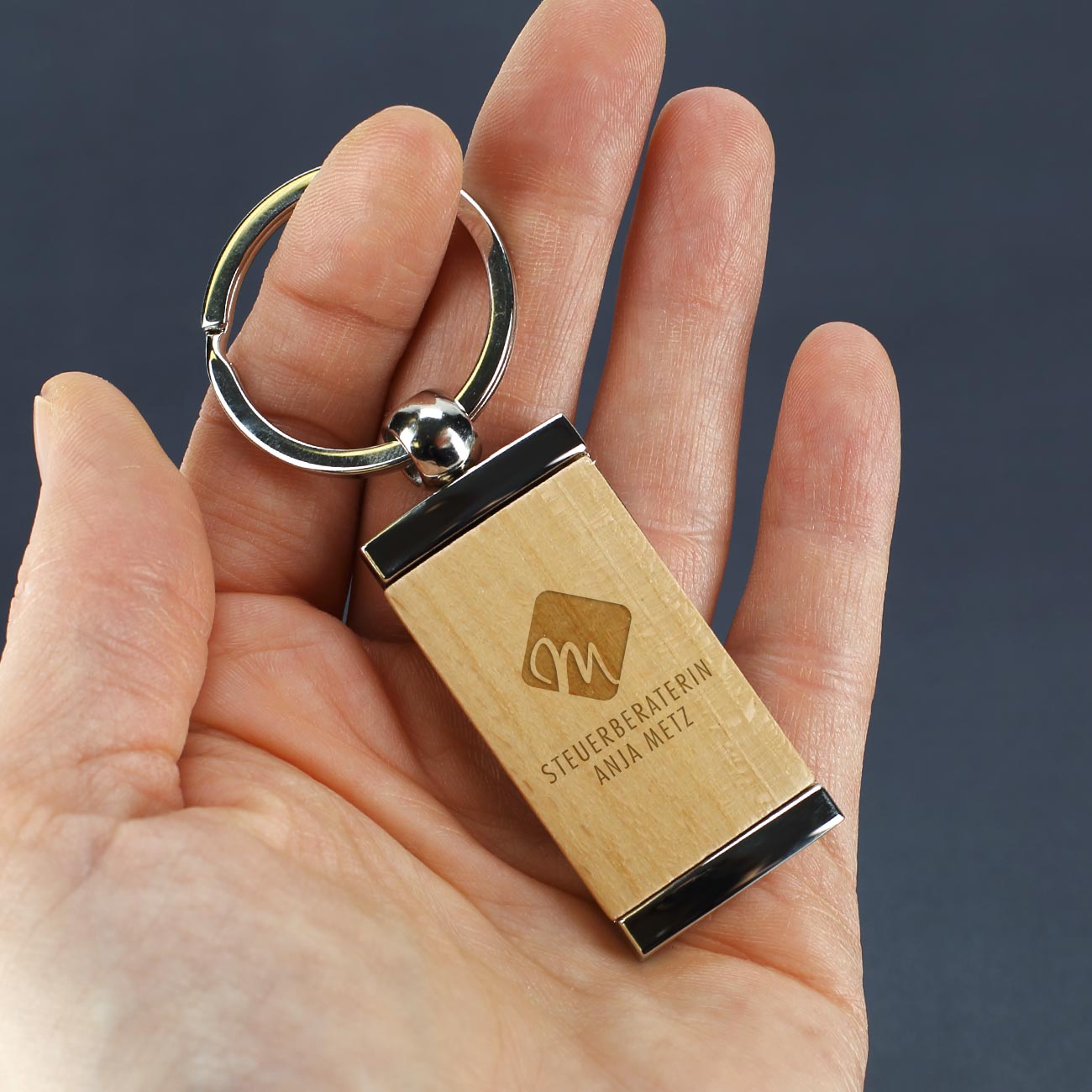 Metall Schlüsselanhänger mit graviertem Holzeinsatz und eigenem Firmen- und Unternehmenslogo Beispiel Steuerbüro quer